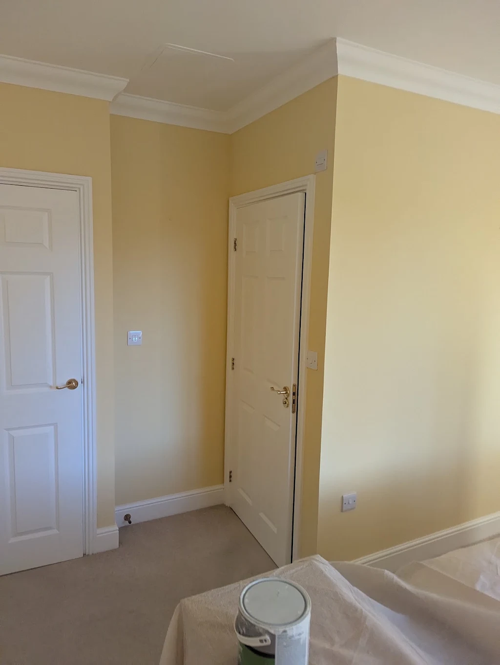 Freshly painted bedroom in warm yellow with crisp white woodwork