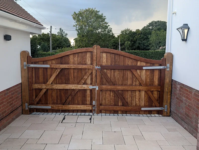 Stained timber double gate on a driveway at dusk